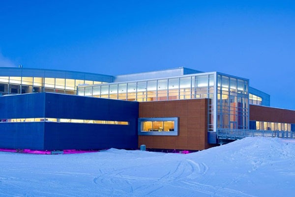 Modern research facility in a snowy landscape, featuring large windows and a sleek design, emphasizing climate research initiatives.