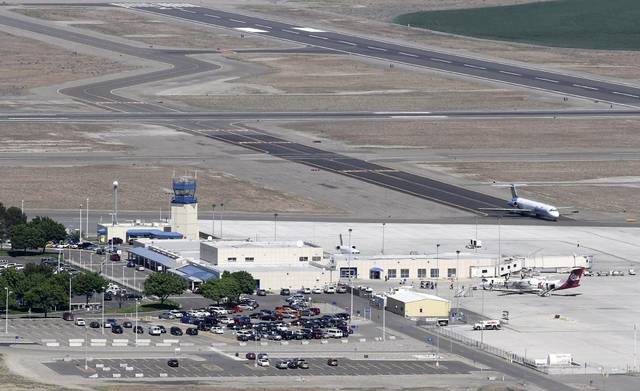Aerial view of a regional airport featuring a control tower, terminal building, parked aircraft, and an adjacent parking lot.